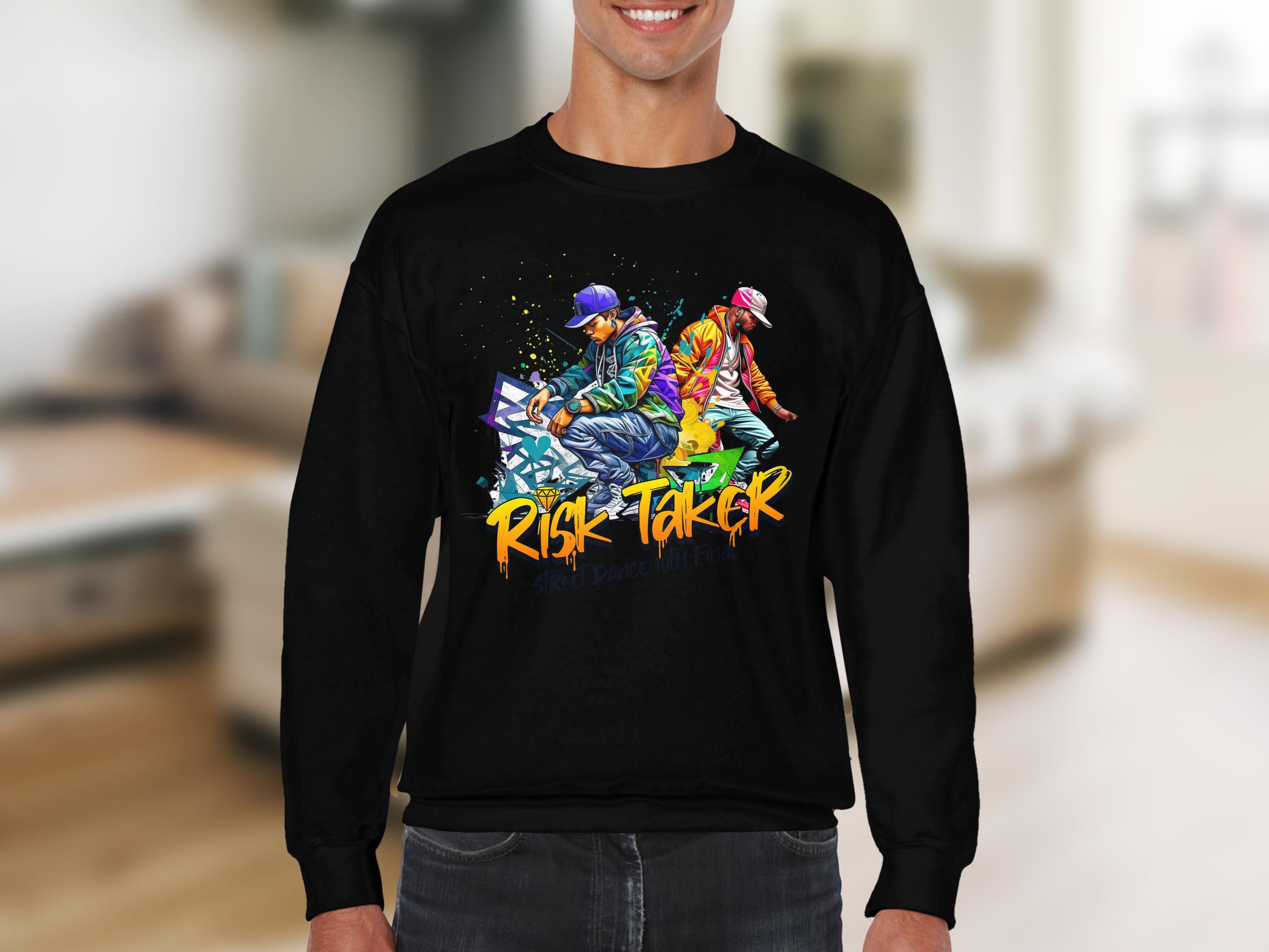 A person wears a black sweatshirt featuring vibrant street dance graphics and Risk Taker text from Garment Graphics. The urban-style piece is showcased against a blurred indoor backdrop, capturing movement and energy.