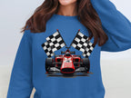 A person in a Garment Graphics blue sweatshirt with a red racing car graphic and crossed checkered flags steps into the spotlight. The individual has long brown hair, with their face out of frame.