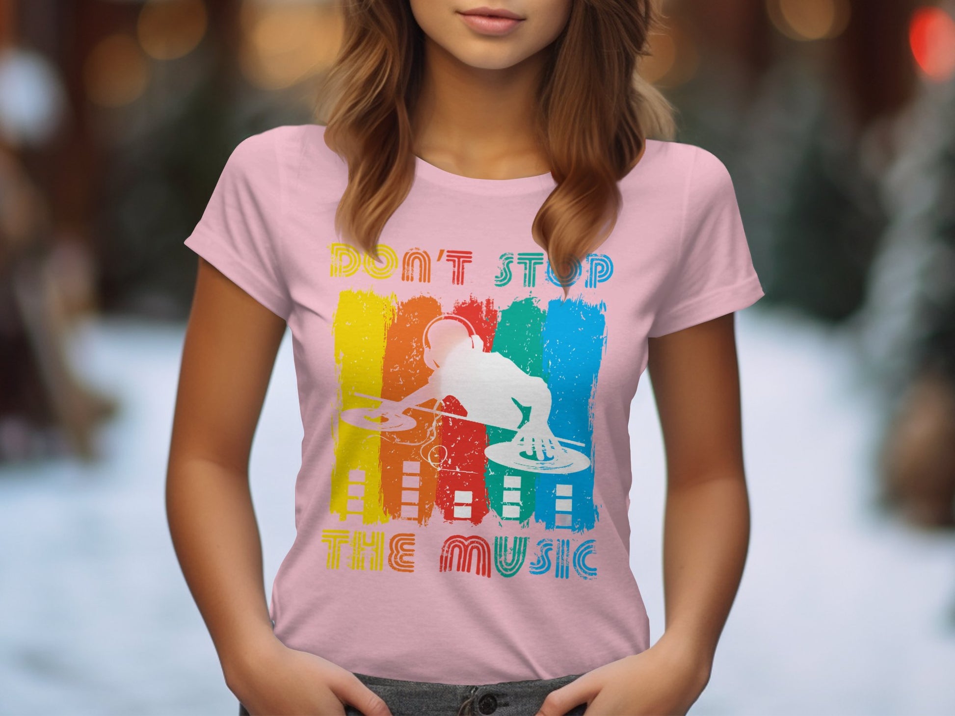 A woman in a vibrant pink Garment Graphics tee, with Dont Stop the Music print, stands amidst snowy trees and twinkling lights. The colorful DJ graphic design is perfect for music lovers, complementing the rhythm of the blurred winter landscape.