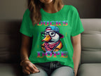 A person relaxes on a gray sofa in a green T-shirt from Garment Graphics, showcasing a duck with cap, glasses, and scarf labeled Ducks Dope in vibrant letters. Their long hair falls over their shoulders, completing the look.