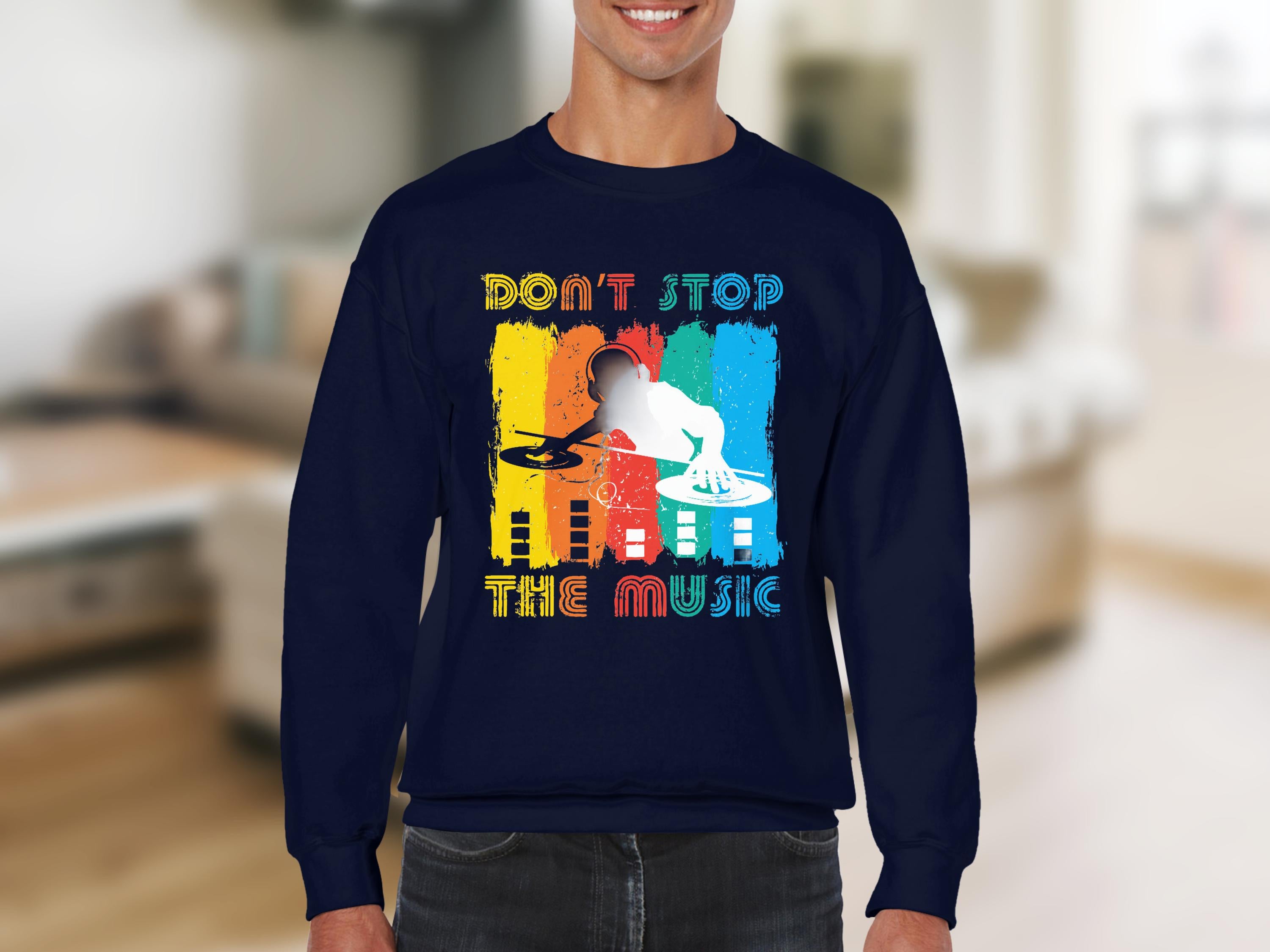 A person wears a Garment Graphics navy blue sweatshirt featuring a vibrant DJ design and the phrase Dont Stop the Music, set against a backdrop of bright paint strokes and abstract designs. A must-have for music enthusiasts.