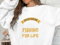 A person wears a Garment Graphics graphic sweatshirt with the bold yellow phrase Father and Son Fishing for Life. Their face is partially obscured by their hair and a raised arm, giving an effortlessly mysterious look.