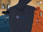 A flat lay featuring trendy Garment Graphics apparel: a navy hoodie with the Scania logo. Surrounding it are black headphones, edgy sunglasses, stylish jeans, an orange button-up shirt, a smart watch, eyeglasses, and keys on a wooden surface.