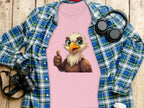 The Garment Graphics pink cartoon T-shirt with an eagle giving a thumbs up, placed on a plaid shirt, is perfect for animal lovers and is surrounded by a camera, headphones, and cup on a wooden surface.