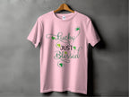 The Royal Mail - 24 Tracked t-shirt is a classic fit in pink with the phrase Lucky Just Blessed, featuring green shamrock motifs and decorative swirls, set against a dark gray background to blend style and luck.