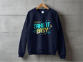 A black sweatshirt hangs on a wooden hanger against a gray concrete wall. Designed by Garment Graphics, it features Take It Easy in colorful letters with musical notes and arrows. Unisex sizing makes it ideal for sharing your laid-back style.