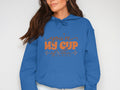 Against a plain backdrop, someone wears Garment Graphics blue hoodie with the Youre my cup of tea design in orange across the chest, hands in the front pocket, embodying perfect tea hoodie vibes.