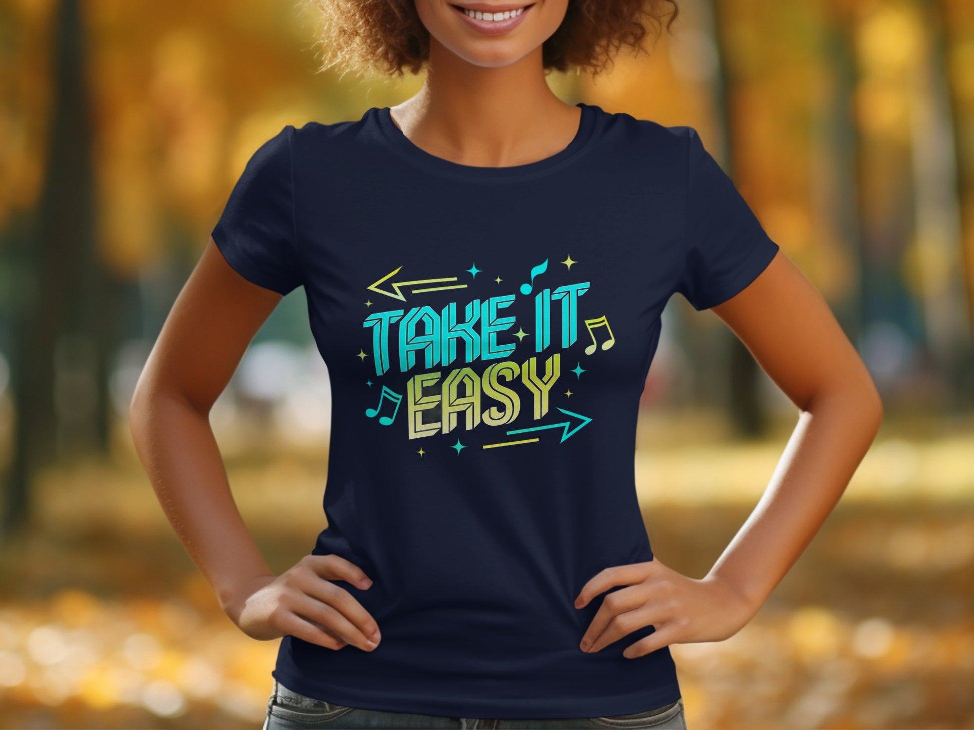A person wears a navy blue Garment Graphics T-shirt featuring the stylish Take It Easy design with vivid arrows, musical notes, and stars. The background highlights a blurred view of trees in fall foliage.
