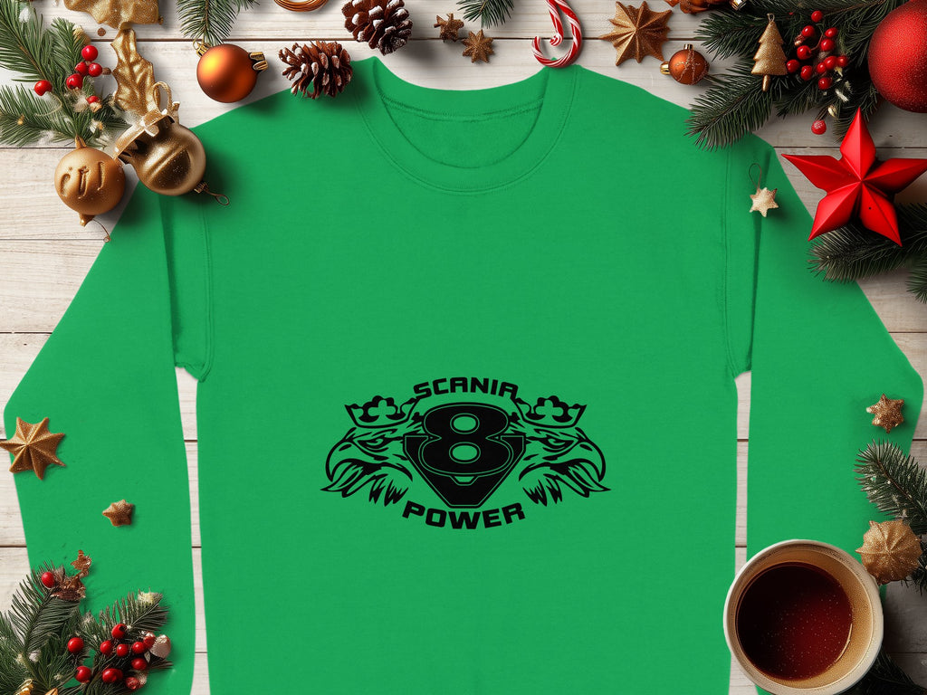 A Garment Graphics green sweatshirt featuring the Scania Power 8 logo and eagle graphics is displayed on a wooden table, accompanied by pine branches, ornaments, and a steaming coffee cup, creating a festive Christmas atmosphere.