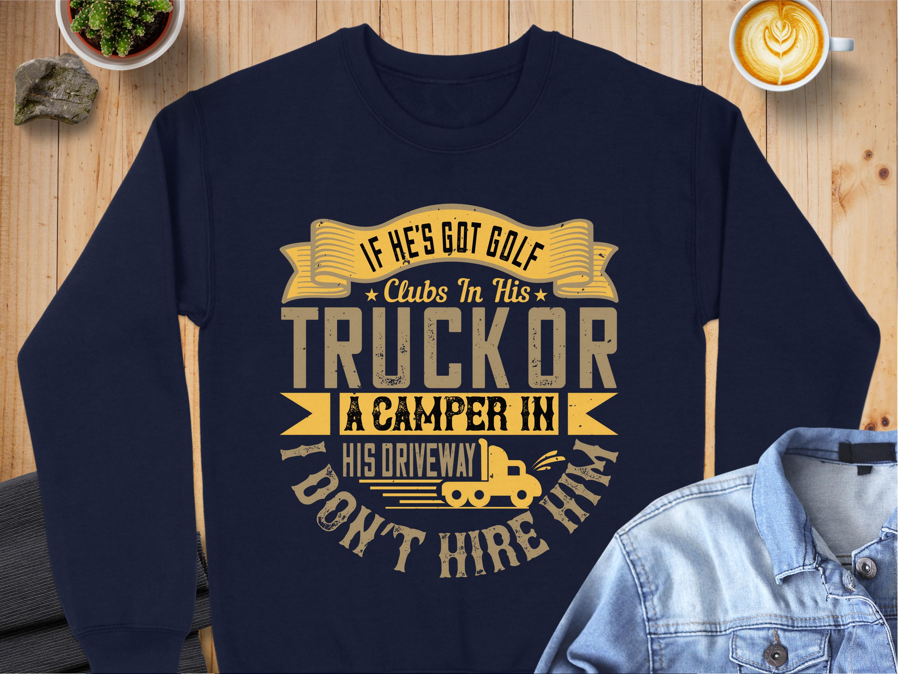A Garment Graphics sweatshirt on wood displays the text: If hes got golf clubs in his truck or a camper in his driveway, I dont hire him, with a camper graphic. Nearby are casual items like a denim shirt, coffee, and small plants for added charm.