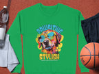 Garment Graphics green sweatshirt showcases a vibrant dog in sunglasses, ideal for dog lovers. It features Pawsitive Stylish and Chillin Like a Canine Villain text. Displayed with a basketball, black shorts, towel, and water bottle.