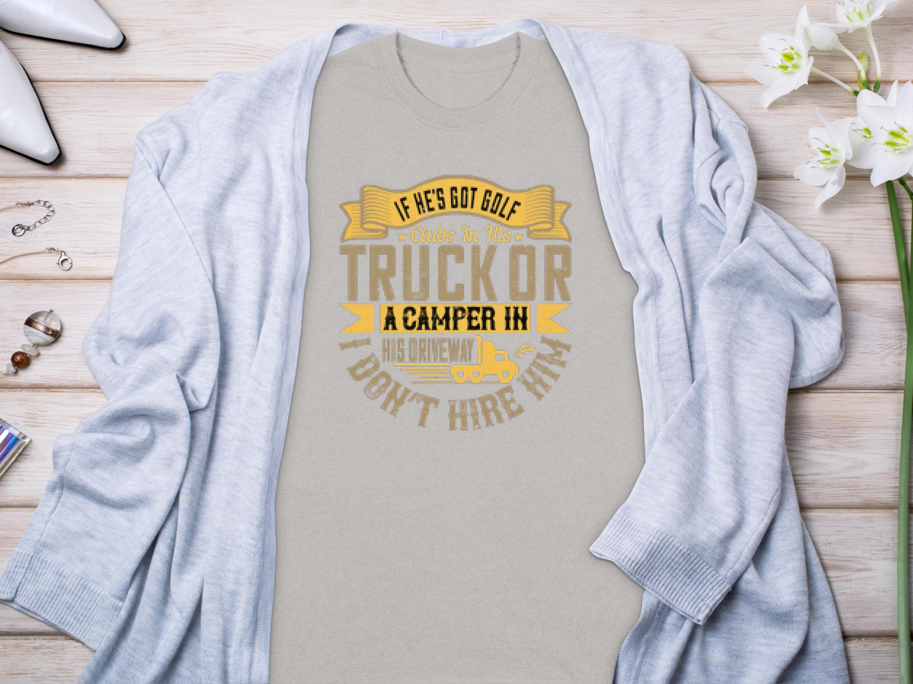 Light gray Garment Graphics t-shirt with the text If hes got golf clubs in his truck or a camper in his driveway, dont hire him in yellow and gray. Ideal for camping or golf fans, styled with a cardigan and surrounded by white flowers and jewelry.