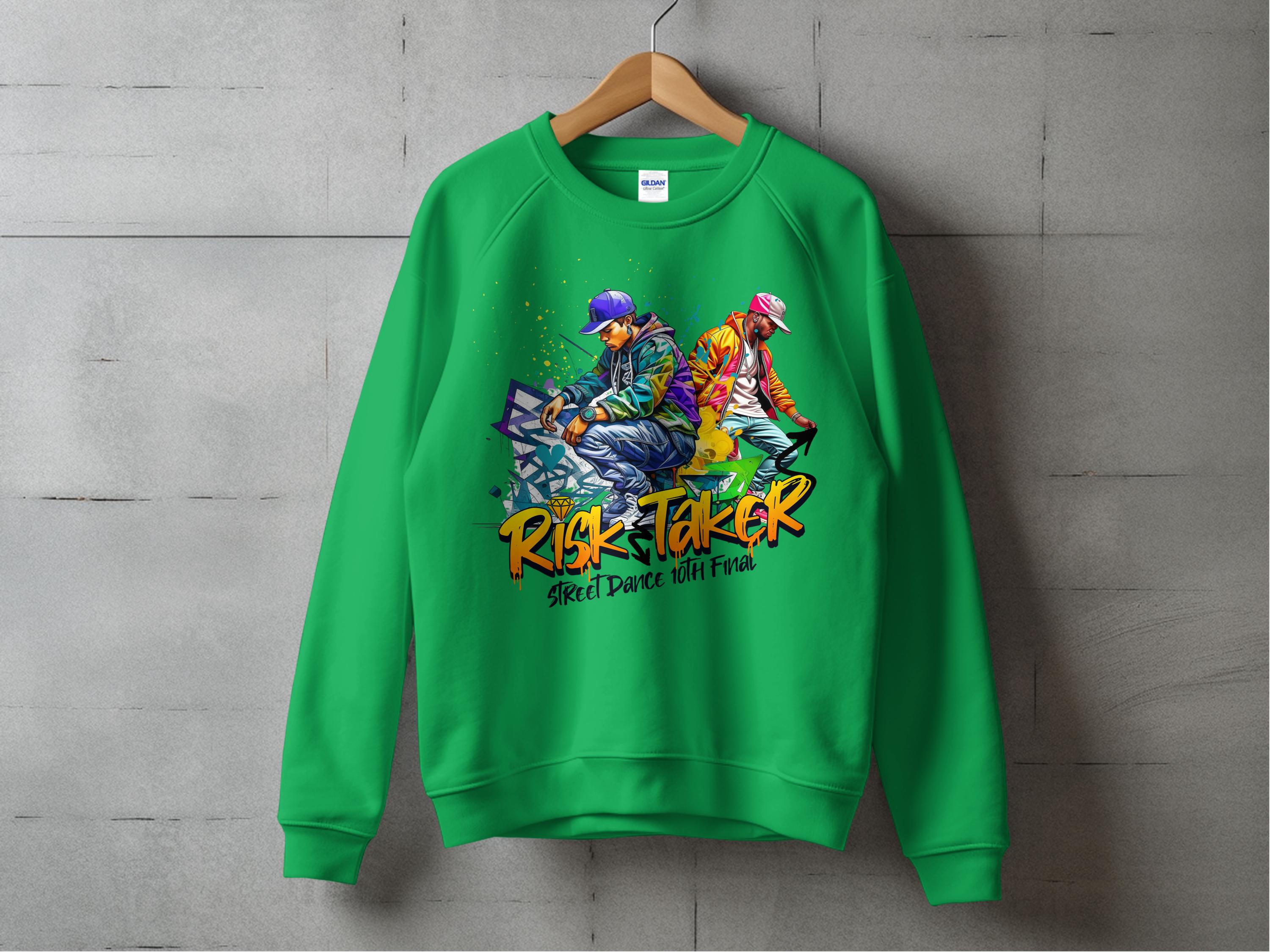 A green unisex sweatshirt by Garment Graphics hangs against a concrete wall, featuring street dance graphics of two stylized figures in vibrant outfits on skateboards with bold text: Risk Taker and Street Dance with Pride, completing its urban style.