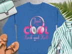 Garment Graphics blue sweatshirt, adorned with Just be Cool, Rock and Roll and headphones, is styled alongside tan sandals, a mint handbag, a striped shirt, a watch, and a fern on a gray surface—ideal for fashion lovers and music enthusiasts.