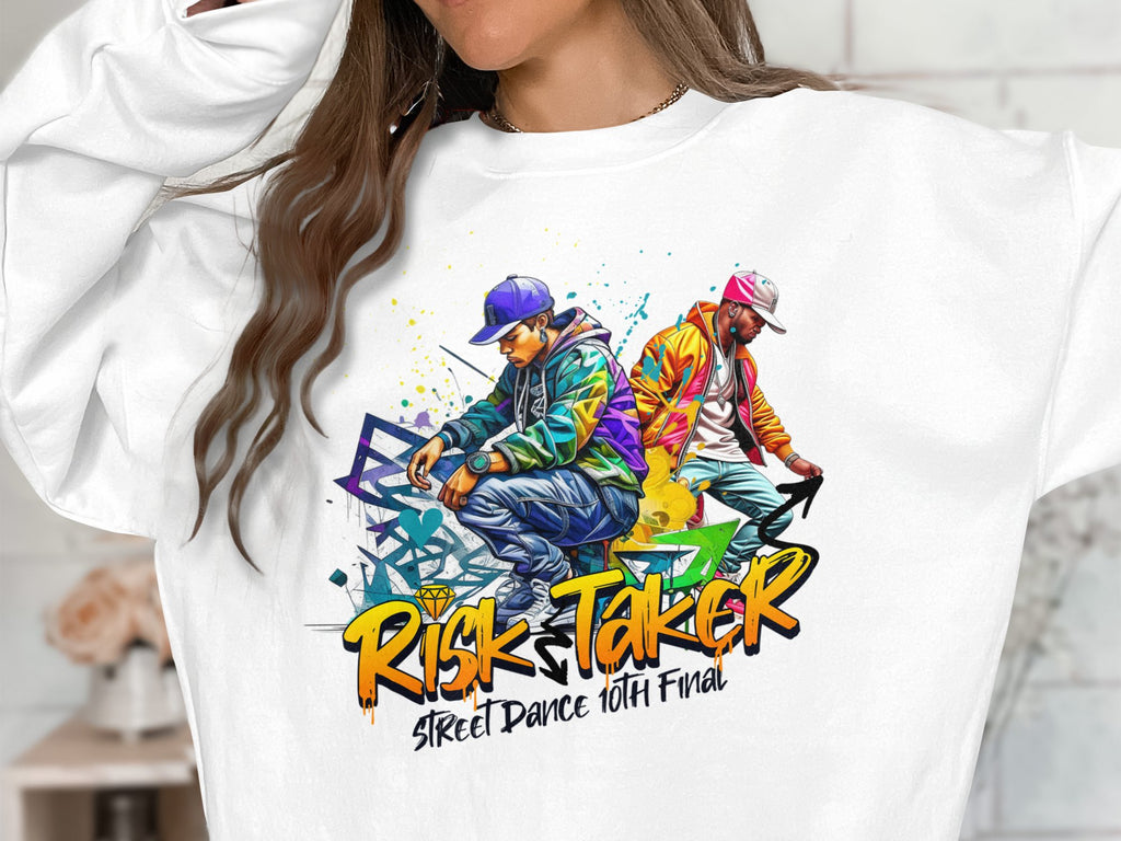 A person wears a white Garment Graphics sweatshirt featuring a bold graphic of two streetwear-clad men dancing. Below, the text Risk Taker Street Dance 10th Final celebrates the street dance finals.