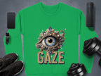 The Garment Graphics unisex graphic sweatshirt showcases an ornate eye design above GAZE, surrounded by a smartphone, smartwatch, wireless speaker, black shoes, and dumbbells on a gray background.