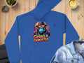 Garment Graphics blue hoodie, featuring Gorilla Gangster artwork—a gorilla in a hat, sunglasses, and suit—is ideal for streetwear fans. Its showcased on wood beside a denim jacket, coffee, and a plant.