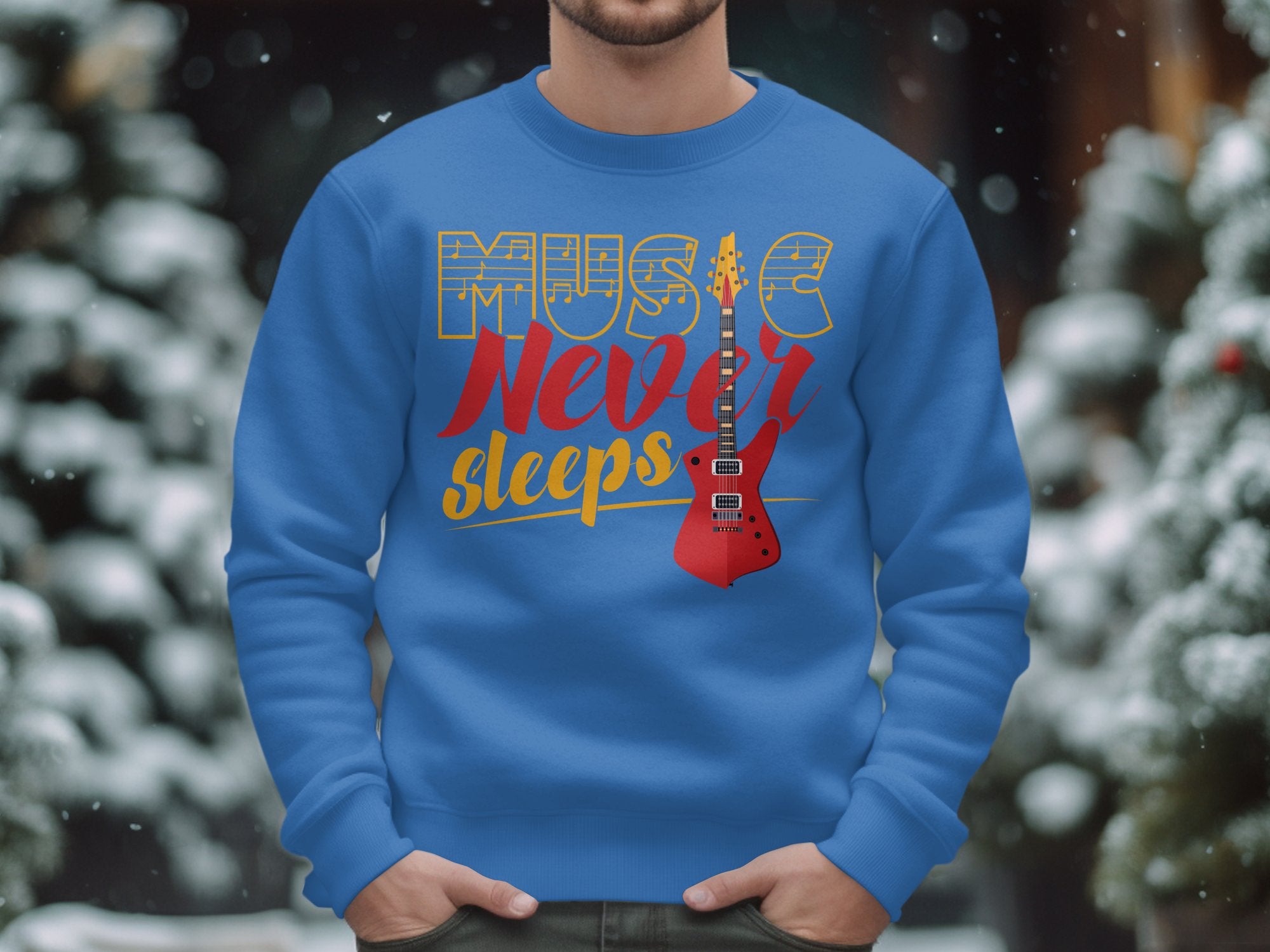 Amidst a snowy backdrop, someone sports a vibrant blue sweatshirt by Garment Graphics featuring a red electric guitar and bold Music Never Sleeps text, ideal for music lovers. Snow-covered trees blur serenely in the background.