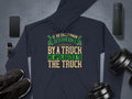 A Garment Graphics navy hoodie sports the witty quote If an Englishman gets run down by a truck, he apologizes to the truck in green and beige. Its surrounded by essentials: smartphone, smartwatch, headphones, wireless speaker, athletic shoes, and a dumbbell.