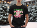 A person stands in the snow wearing a Garment Graphics classic fit black T-shirt. The shirt features a cartoon figure holding a rose in their mouth with HANDS OFF! printed on the front. Snow-covered trees create a serene backdrop for this eye-catching Hands Off T-Shirt.