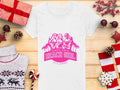 A white semi-fitted womens tee, branded Garment Graphics, displays a pink graphic of three women, palm trees, and the text Always Party Beach Girl above Kittl Apparel. The t-shirt is placed on a wooden surface with gifts, pine cones, berries, a candy cane, and a sweater.