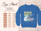 Size chart image for Garment Graphics Gildan 18000 heavy blend crewneck sweatshirt, showing unisex sizes S to 5XL with width and length. This blue sweatshirt has a Beach Vibes design with a pink car, surfboard, and waves, reflecting a retro roadtrip style.