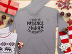 A Garment Graphics Patience Tested Hoodie, featuring the text I had my patience tested Im negative in gray, is surrounded by gifts, a classic fit sweater, pine cones, candy, and Christmas decorations on wood. This medium-heavy fabric hoodie is ideal for the festive season.
