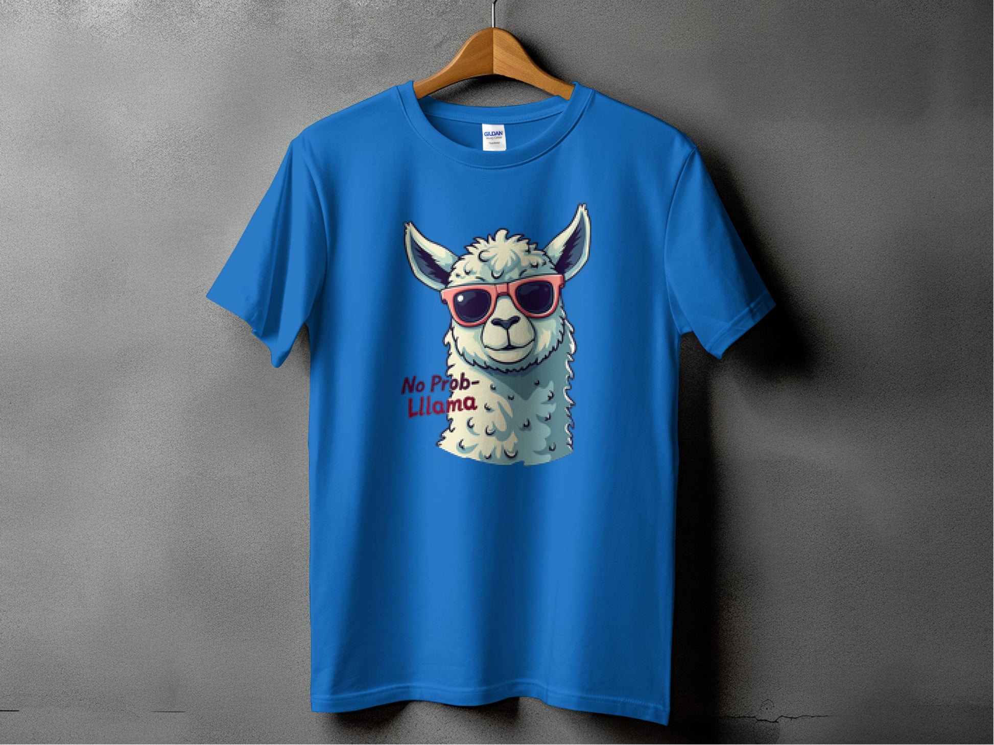 A Garment Graphics blue Llama T-shirt features a llama with red sunglasses and playful No Prob-llama text. Ideal for family sizes, it hangs on a wooden hanger against a gray background.