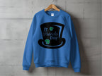 The Garment Graphics blue sweatshirt features a black top hat graphic with green clovers and St. Patricks Day text. Displayed on a wooden hanger against a concrete wall, it embodies festive charm for your celebrations.