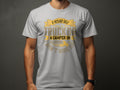 A person wears a light gray Garment Graphics t-shirt featuring a design with stylized text: If hes got golf clubs in his truck or a camper in his driveway, dont hire him, cleverly blending camping and golf with simple line art of a truck and camper.