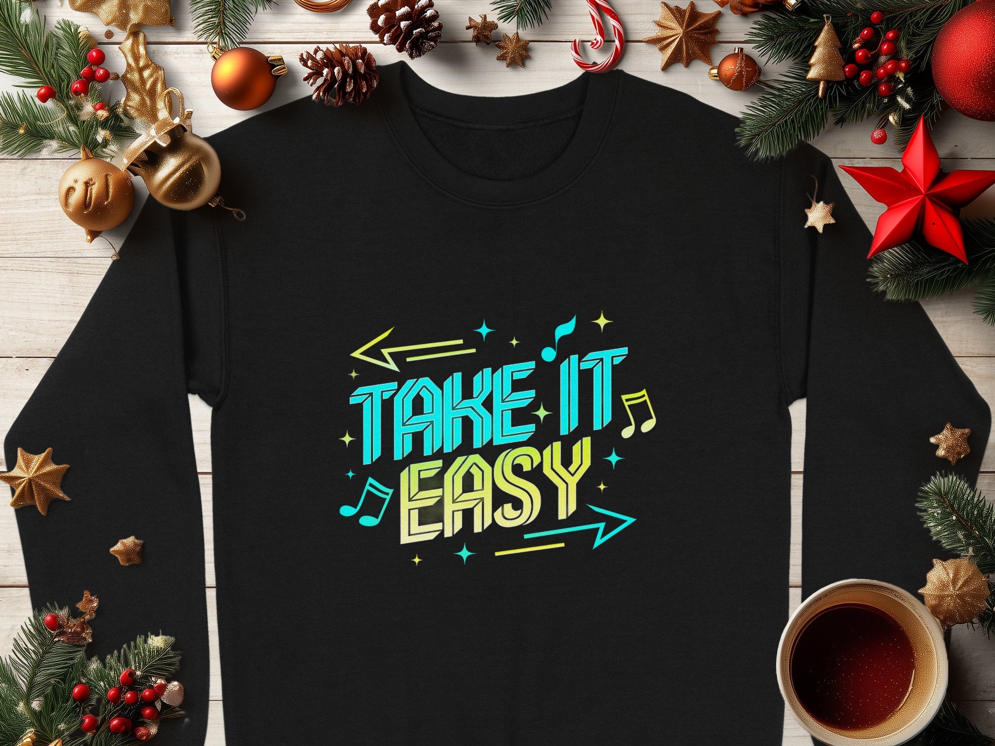 Garment Graphics offers a comfy black unisex sweatshirt featuring Take It Easy in vibrant blue and yellow. Musical notes, arrows, pine branches, ornaments, and a mug enhance the design on a wooden surface for a casual and relaxed vibe.
