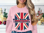 Amidst a festive kitchen, a woman wears a Garment Graphics pink sweatshirt with a distressed British flag and the phrase Dont Blame Me, I Didnt Vote For Him. Available in unisex sizes for versatile styling.