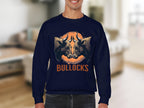 A man dons a Garment Graphics loose-fit navy sweatshirt showcasing an eye-catching graphic of two bulls facing each other with BULLOCKS below, set against a softly blurred indoor backdrop with a beige sofa and light walls.
