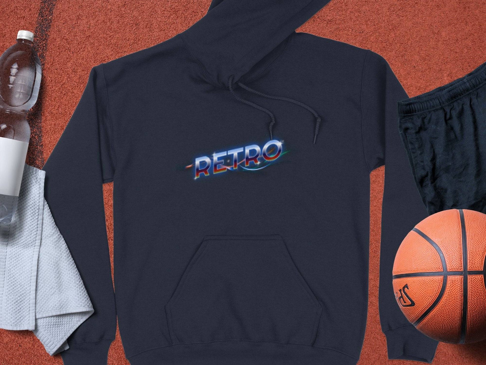 The Garment Graphics black hoodie features RETRO in vibrant, glowing text. Its displayed with a basketball, black shorts, a white towel, and a water bottle for a trendy look.