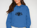 A person in a classic fit blue hoodie by Garment Graphics, showcasing two griffins beside a stylized 8 with Scania Power Eight Hoodies text on the front. They have long brown hair, and the photo is cropped just beyond their shoulders and waist.