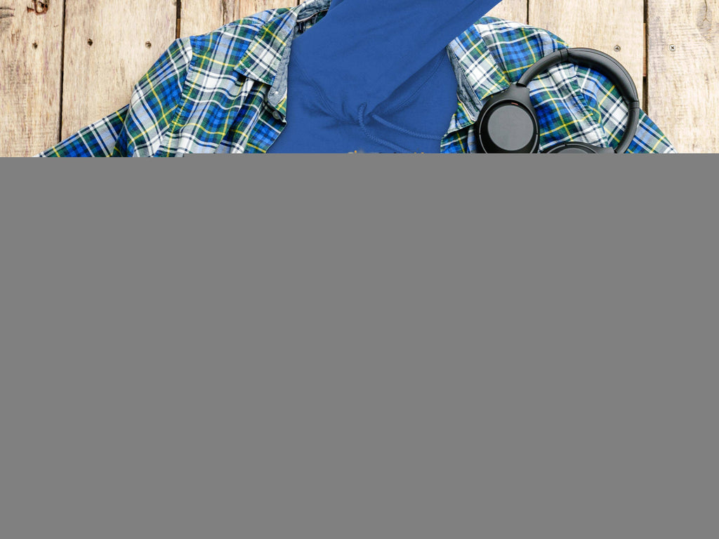 A flat lay displays a Garment Graphics Graphic Bulldog Design Hoodie with CITY KING text. Accompanying it are a plaid shirt, headphones, camera, water bottle, and coffee cup on a wooden surface.