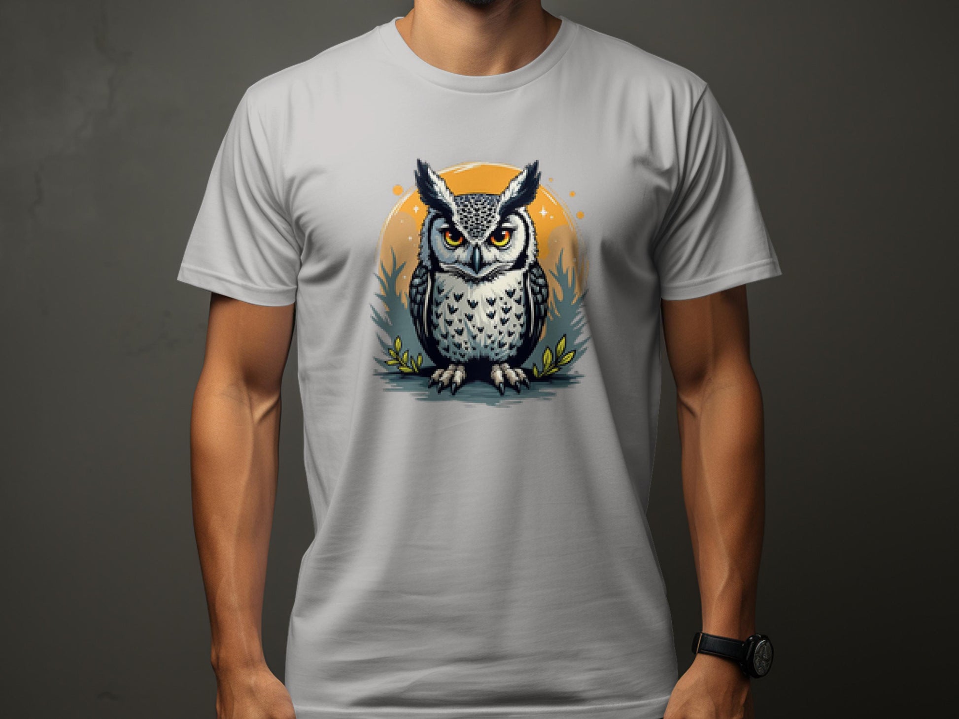 A person wears a Garment Graphics light gray T-shirt featuring an owl print contrasted by an orange circle, striking against a dark background.