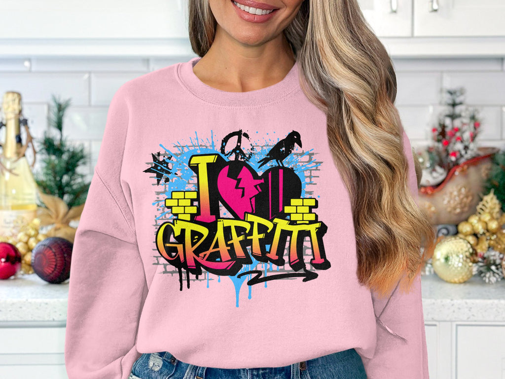 Wearing a Garment Graphics artistic sweatshirt, a person sports a pink top with an urban graffiti design that says I Love Graffiti, featuring bricks, splash effects, and paint drips, standing in a kitchen adorned with holiday decor.