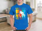 A person wears a blue Garment Graphics T-shirt featuring a DJ design and the text Dont Stop The Music, ideal for music lovers against vibrant bars, capturing the party vibe in a blurred indoor scene.