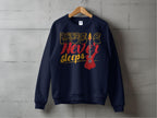 A vibrant navy blue sweatshirt by Garment Graphics hangs on a wooden hanger against a concrete wall. Perfect for music lovers, it features Music Never Sleeps in gold and red with an electric guitar illustration.