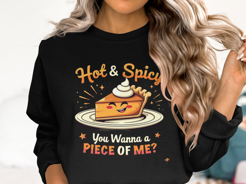 A person with long wavy hair is wearing a stylish Garment Graphics sweatshirt featuring a smiling slice of pie topped with whipped cream. Above, it says Hot & Spicy, and below, You Wanna a Piece of Me? This unisex piece is perfect for fans of bold, playful fashion.