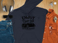 A navy blue hoodie from Garment Graphics features a Enjoy Classic Car print and car graphic, embodying community spirit, displayed amid headphones, sunglasses, blue jeans, an orange shirt, a watch, clear glasses, and keys on wood.