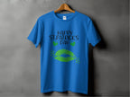 A Garment Graphics T-shirt on a wooden hanger features bold green lips, two clovers, and the festive Happy St. Patricks Day text against a gray background.