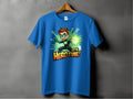 A vibrant blue Garment Graphics t-shirt on a wooden hanger against a gray wall features a superhero cartoon character in a green suit with a glowing hand and the text Its Hero Time! Available in family sizing for heroic style for everyone.