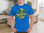 A person in a Garment Graphics Happy Patricks Day T-Shirt featuring a bold beer mug, shamrocks, and Happy Patricks Day text design stands against the bustling, blurred background of St. Patrick’s indoor festivities.