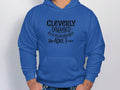 Sporting a Garment Graphics cleverly disguised hoodie, featuring a blue design with Cleverly disguised as a responsible adult in black text and two small arrows, they casually rest their hands in the pockets of this playful casual wear.