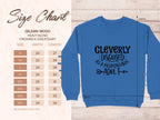 A size chart for the Garment Graphics 18000 crewneck, ideal for adding humor to your wardrobe, accompanies a blue sweatshirt that reads Cleverly disguised as a responsible adult with two arrows. Unisex sizes range from small to 5XL, detailing corresponding width and length measurements.