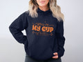 Wrapped in cozy moments, a person wears Garment Graphics navy hoodie with youre my cup of tea in vibrant orange. This comfy hoodie features a front pocket, perfectly contrasting the wearers light wavy hair against a neutral backdrop.