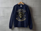 A dark blue sweatshirt by Garment Graphics hangs on a wooden hanger against a gray background, featuring a skull in goggles and helmet graphic, framed by Blackpool 2023 Sweatshirts - Liberty Motorcycles Specialist.