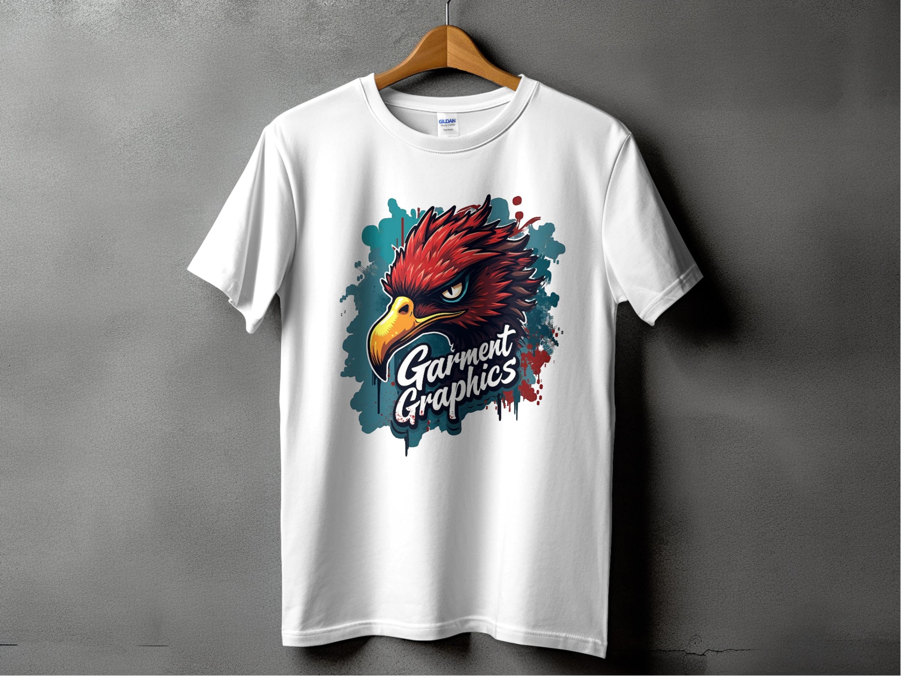A white T-shirt with a classic fit is displayed on a wooden hanger against a gray background, featuring an eagle design with a fierce red bird head above the brand name Garment Graphics in stylized lettering.